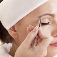 Женщина выщипывает брови