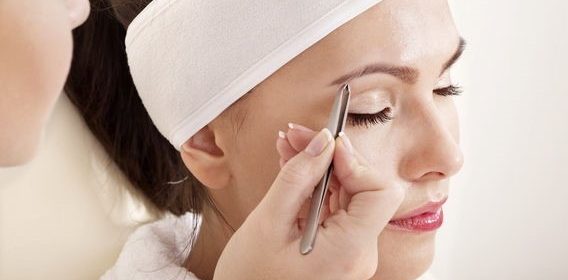 Женщина выщипывает брови