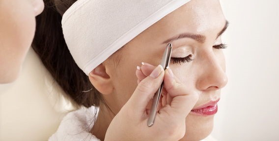 Женщина выщипывает брови Женщина выщипывает брови